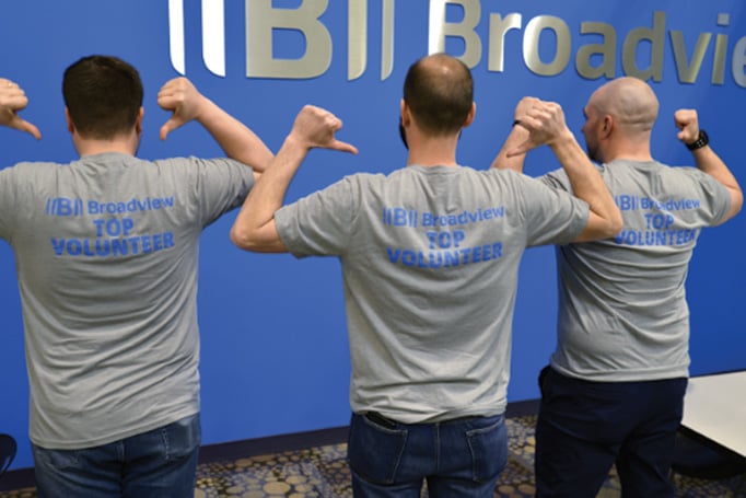Three Broadview FCU employees pointing to their Top Volunteer t-shirts