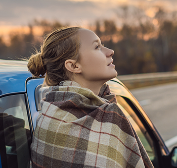 woman leaning against her car