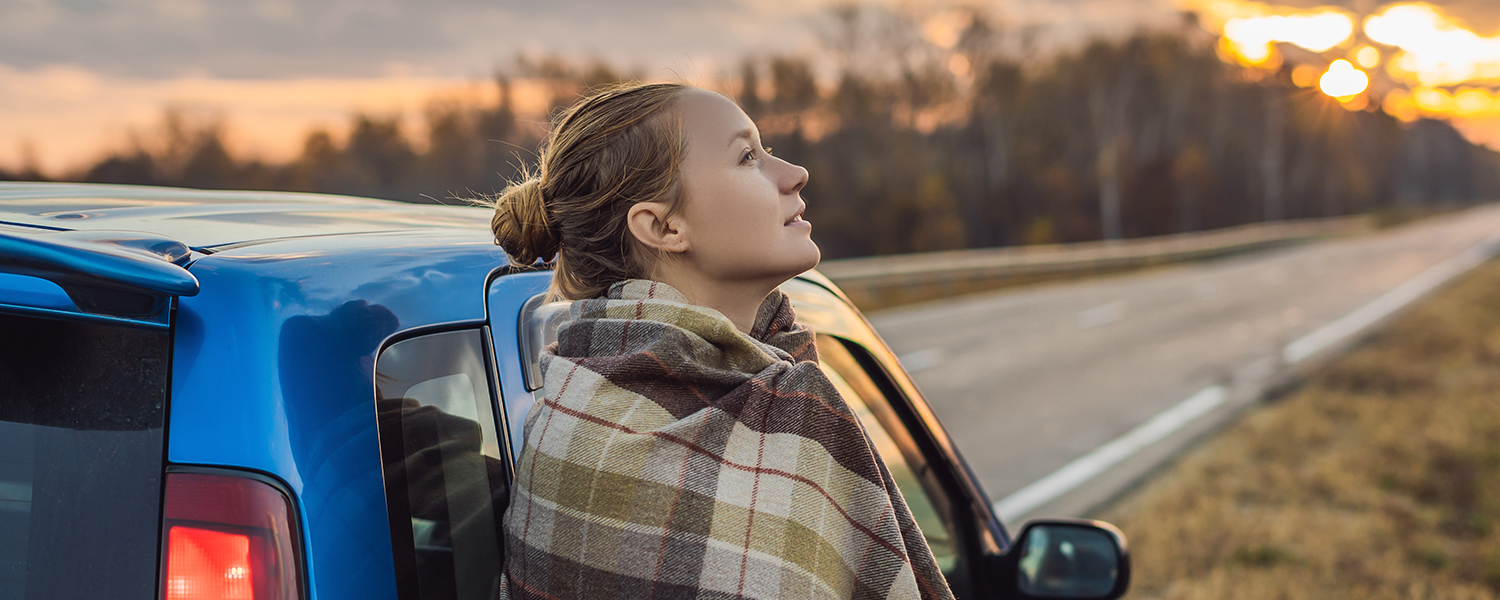 woman leaning against her car