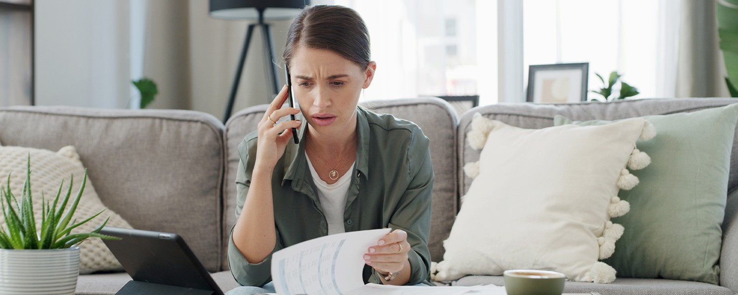 Woman looking stressed while on the phone looking at her finances.
