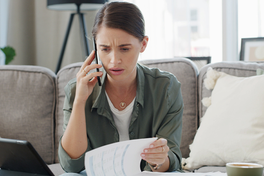 Woman on the phone looking concerned while looking at her statement.