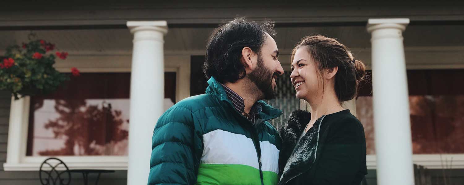 Man and woman smiling at each other in front of their home
