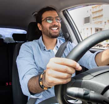 Man in blue shirt happily driving his car