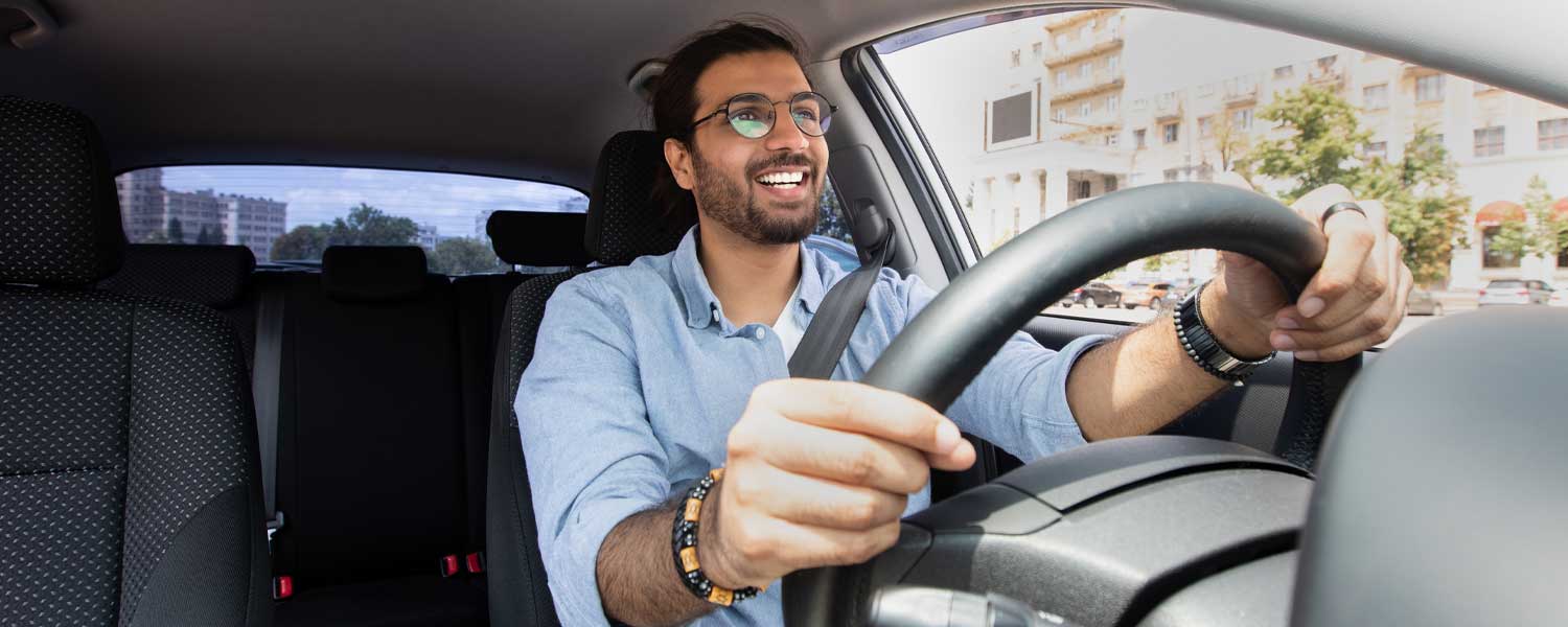 Man in blue shirt happily driving his car