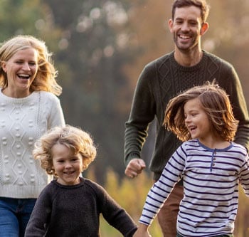 Father, mother, and two kids walking through a field