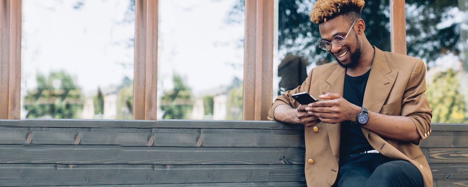 Man looking at phone on a bench