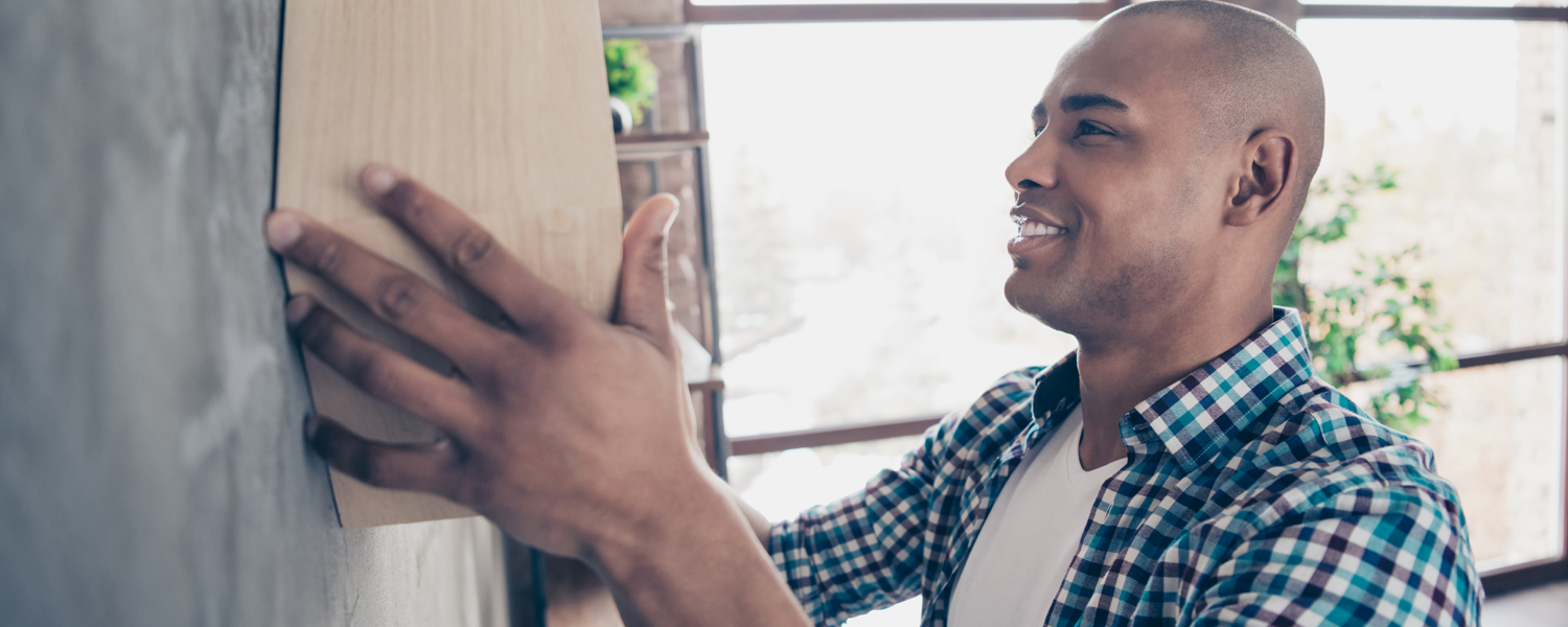 Man in blue plaid hanging a shelf on the wall