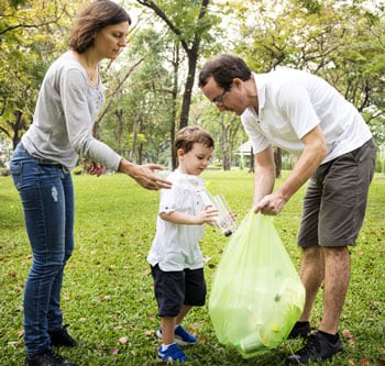 Man, woman, and child picking up trash and putting it into a plastic bag