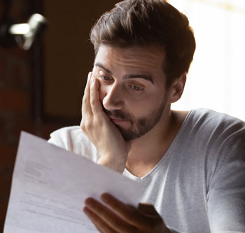 Man staring pensively at a piece of paper