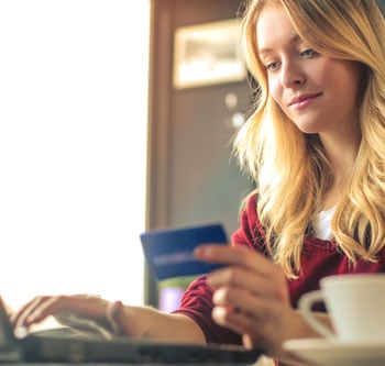 Woman holding her credit card and doing some online shopping