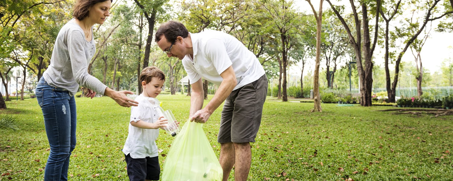 Man, woman, and child picking up trash and putting it into a plastic bag