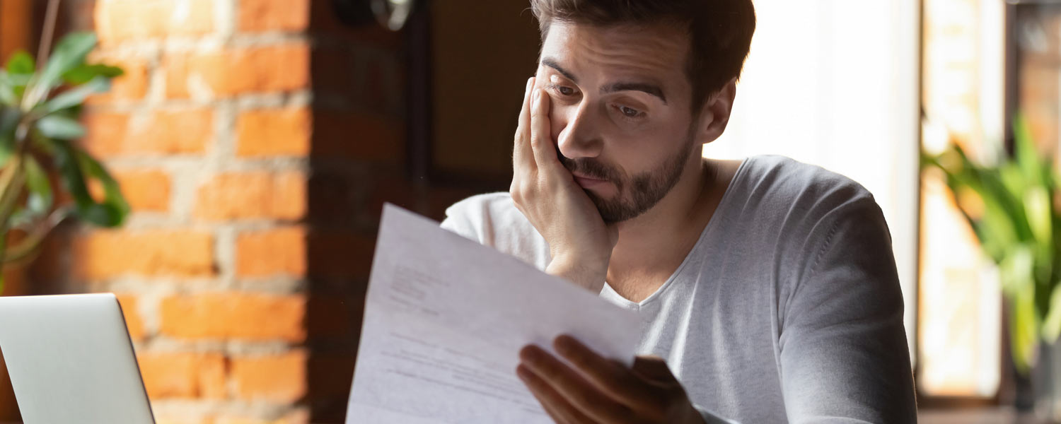 Man staring pensively at a piece of paper