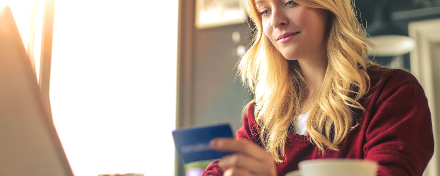 Woman holding her credit card and doing some online shopping