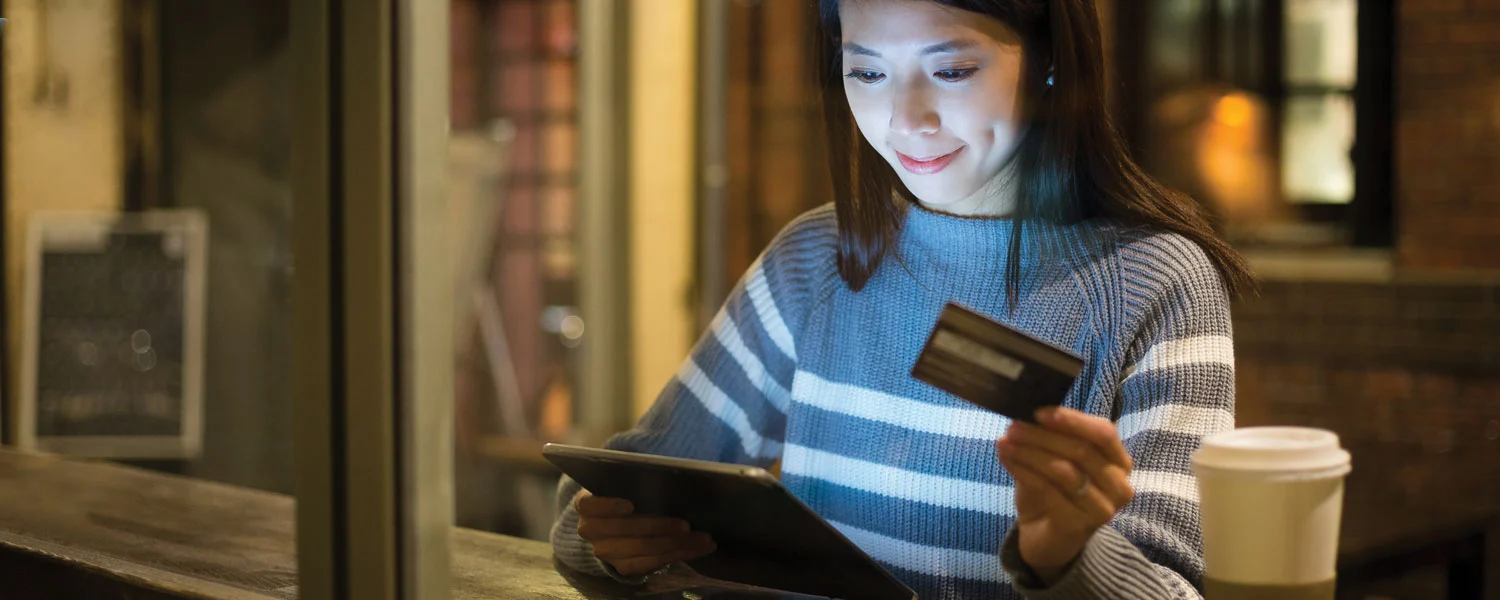 Woman looking at tablet and holding her credit card