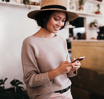 Woman in a hat looking down at her smart phone