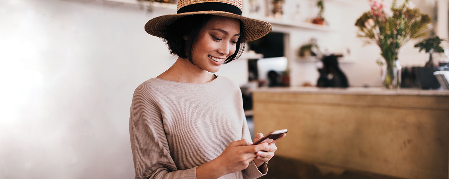 Woman in a hat looking down at her smart phone