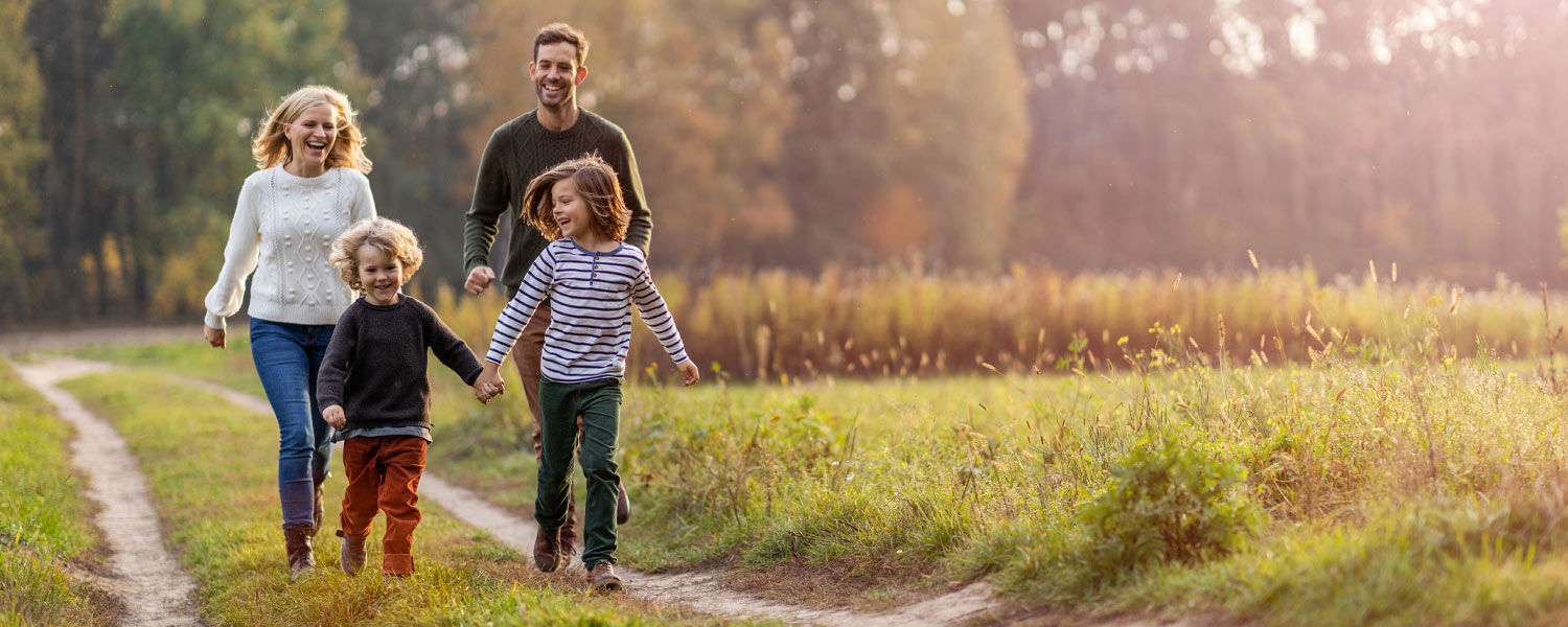 Father, mother, and two kids walking together through a field