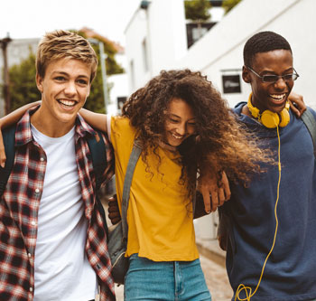 Three teenagers laughing and walking together