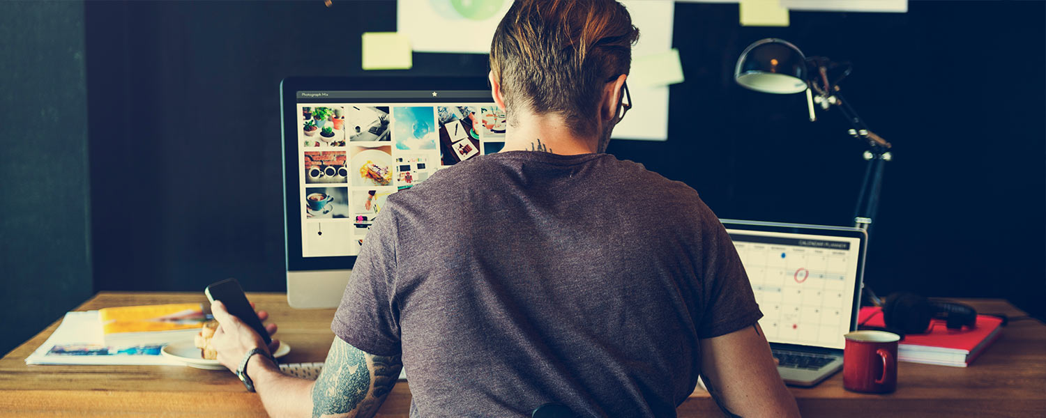 Man working on a computer, laptop, and his phone