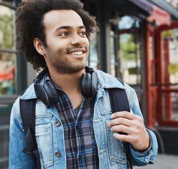 Man in a jean jacket and headphones walking down the street