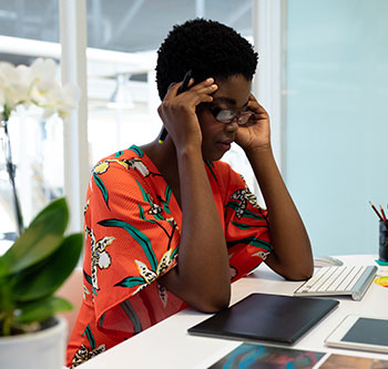 Woman with glasses looking frustrated and staring down at her desk