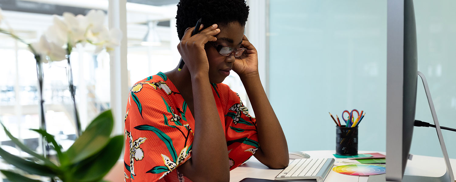 Woman with glasses looking frustrated and staring down at her desk