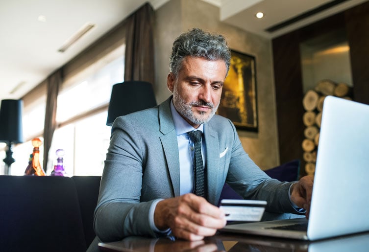 Man holding credit card and working at his laptop