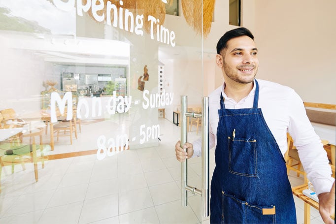 Worker in blue apron opening his store for the day