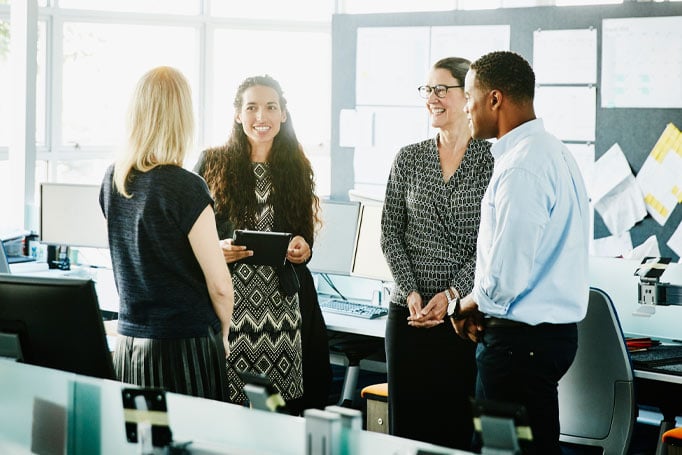 Four people in business casual clothing standing together