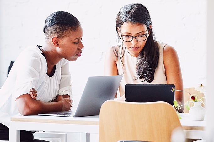 Two women sitting down looking at a laptop