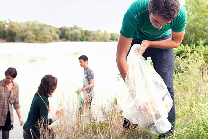 Volunteers picking up trash by a lake
