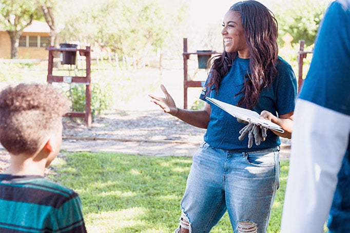 Woman holding gardening gloves smiling at chilld