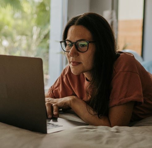 Woman sitting on the bed using laptop