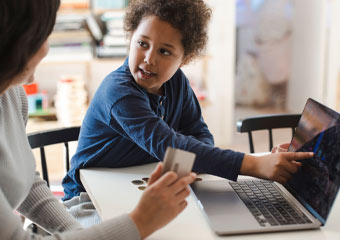 Child pointing to educational material on a laptop screen