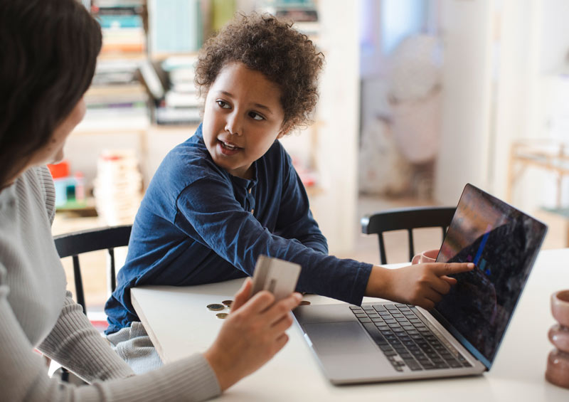 Child pointing to educational material on a laptop screen