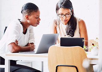 Two women looking at their laptops