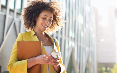 Woman looking at her phone and holding a folder