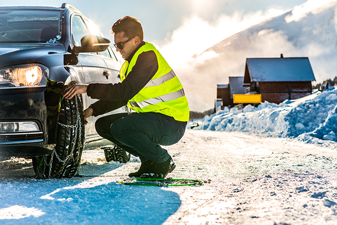 Man changing car tire in the snow