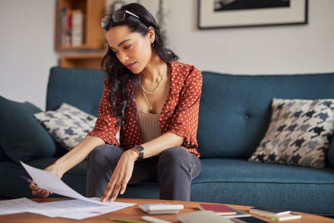 Woman sitting on blue couch and looking at paperwork