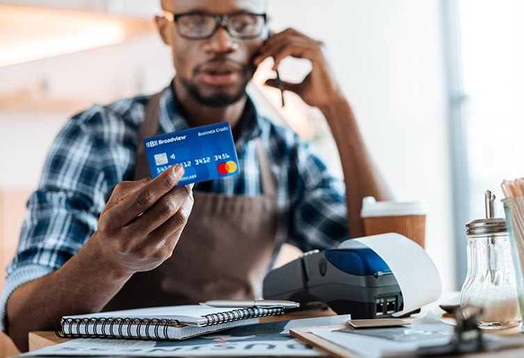 Man on the phone paying a bill with his Broadview Credit Card.