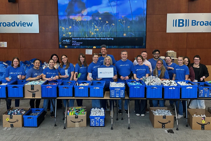 Broadview volunteers wearing Giving for Good shirts surrounded by items to make care kits.