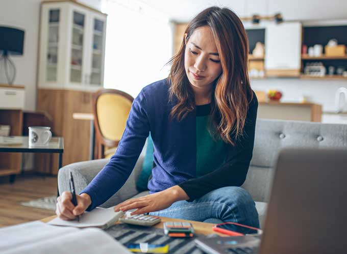 Woman writing on notebook and using calculator