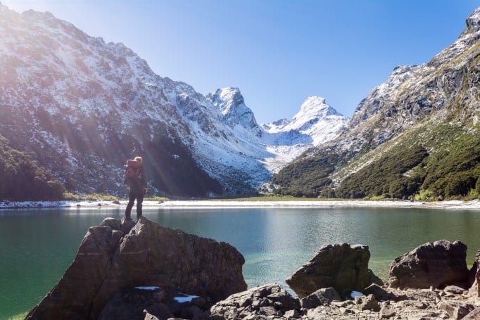 Man standing on rocks overlooking a lake and mountains