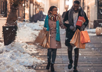 Young couple holding shopping bags and walking through the snow